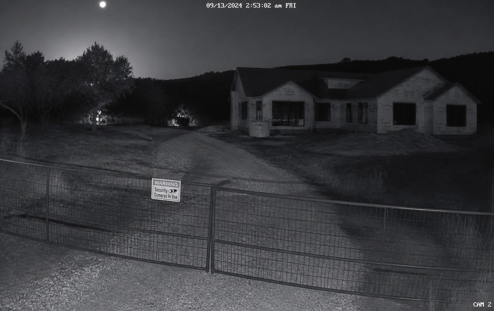 Night camera footage of a gated job site with a home under construction